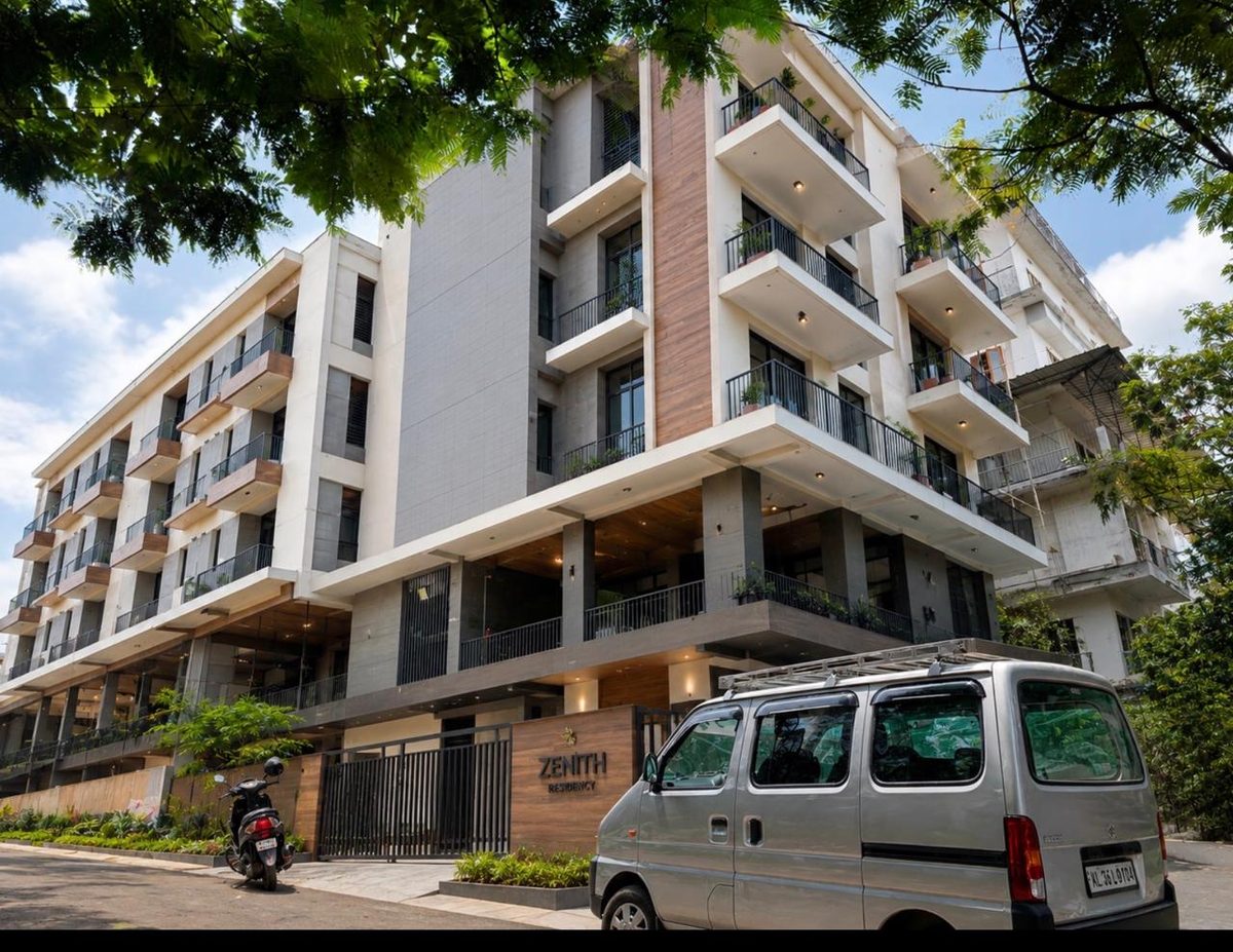 The completed Kalamassery building seen from the street in daylight, balconies across five storeys above an open ground floor